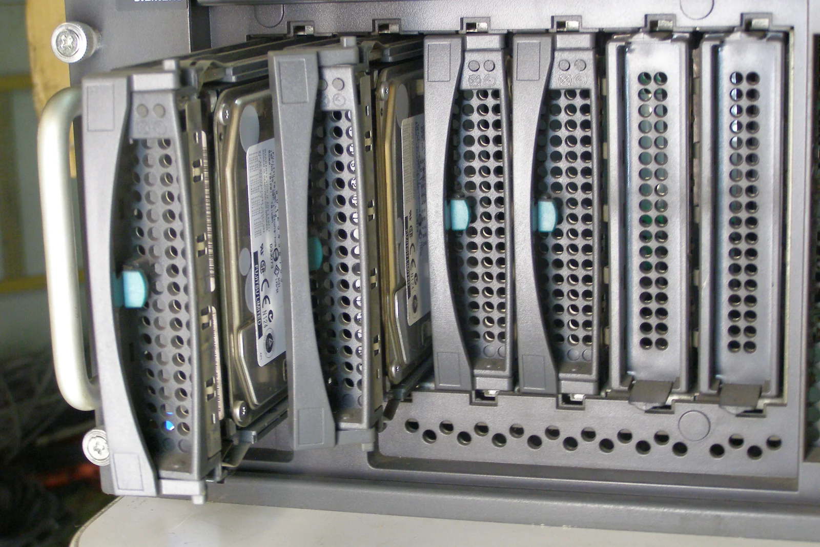 Hot-swap hard-drive trays in an FSC Primergy TX200 S2 server illustrate the physical storage underlying virtual disks